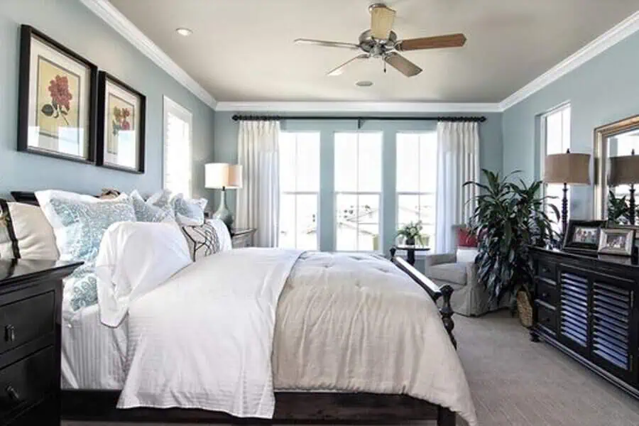 Spacious bedroom with white bedding, blue walls, and large windows letting in natural light