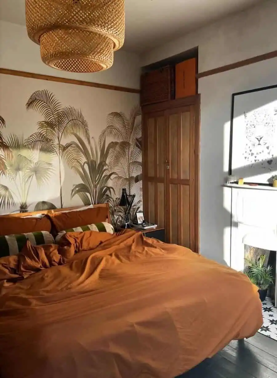 Cozy bedroom with a large bed, tropical-themed wallpaper, wicker light fixture, and wooden wardrobe