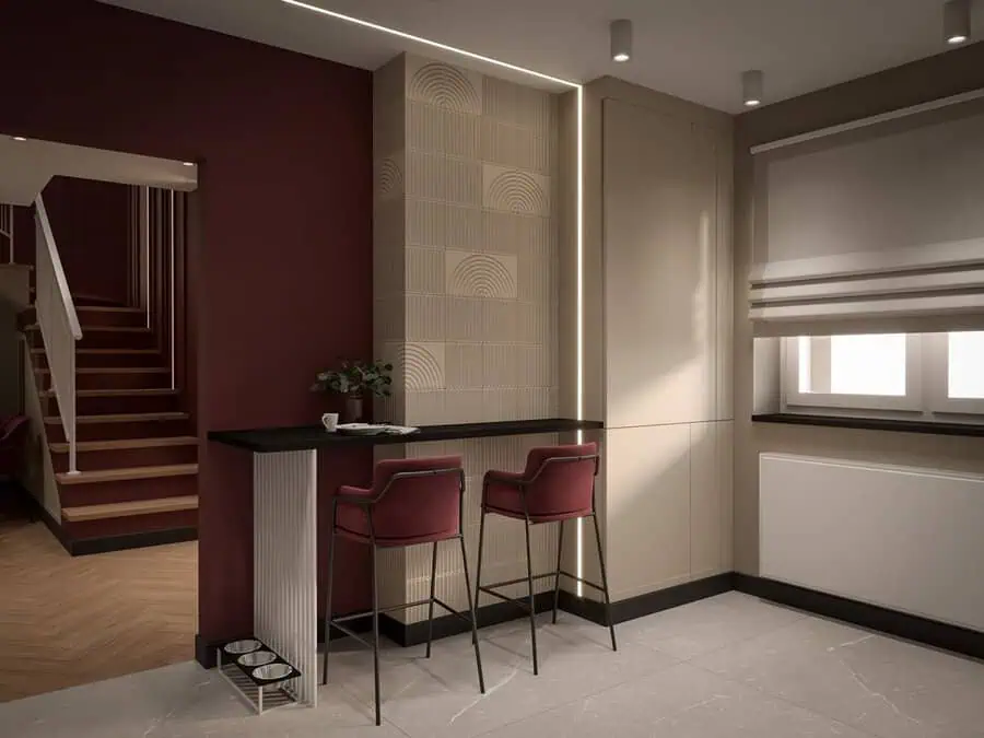 Modern kitchen with dark red accents, minimalist design, and bar area featuring two red bar stools.