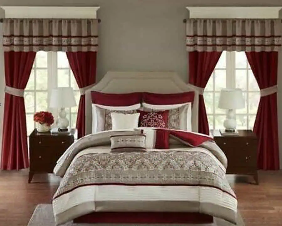 Elegant bedroom with burgundy and beige bedding, matching curtains, and classic wooden nightstands.