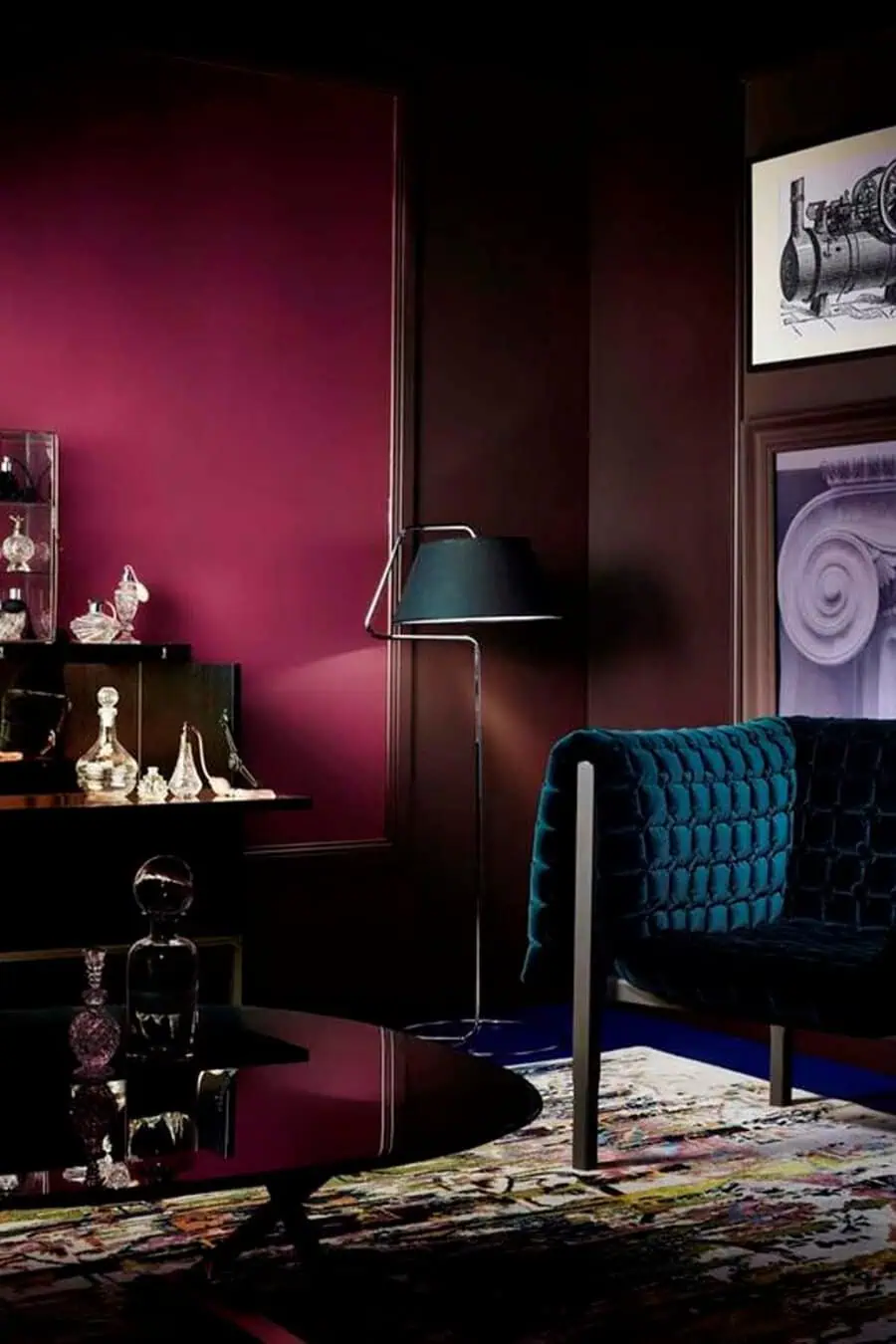 Moody living room with deep burgundy walls, teal velvet seating, and vintage glassware on display.