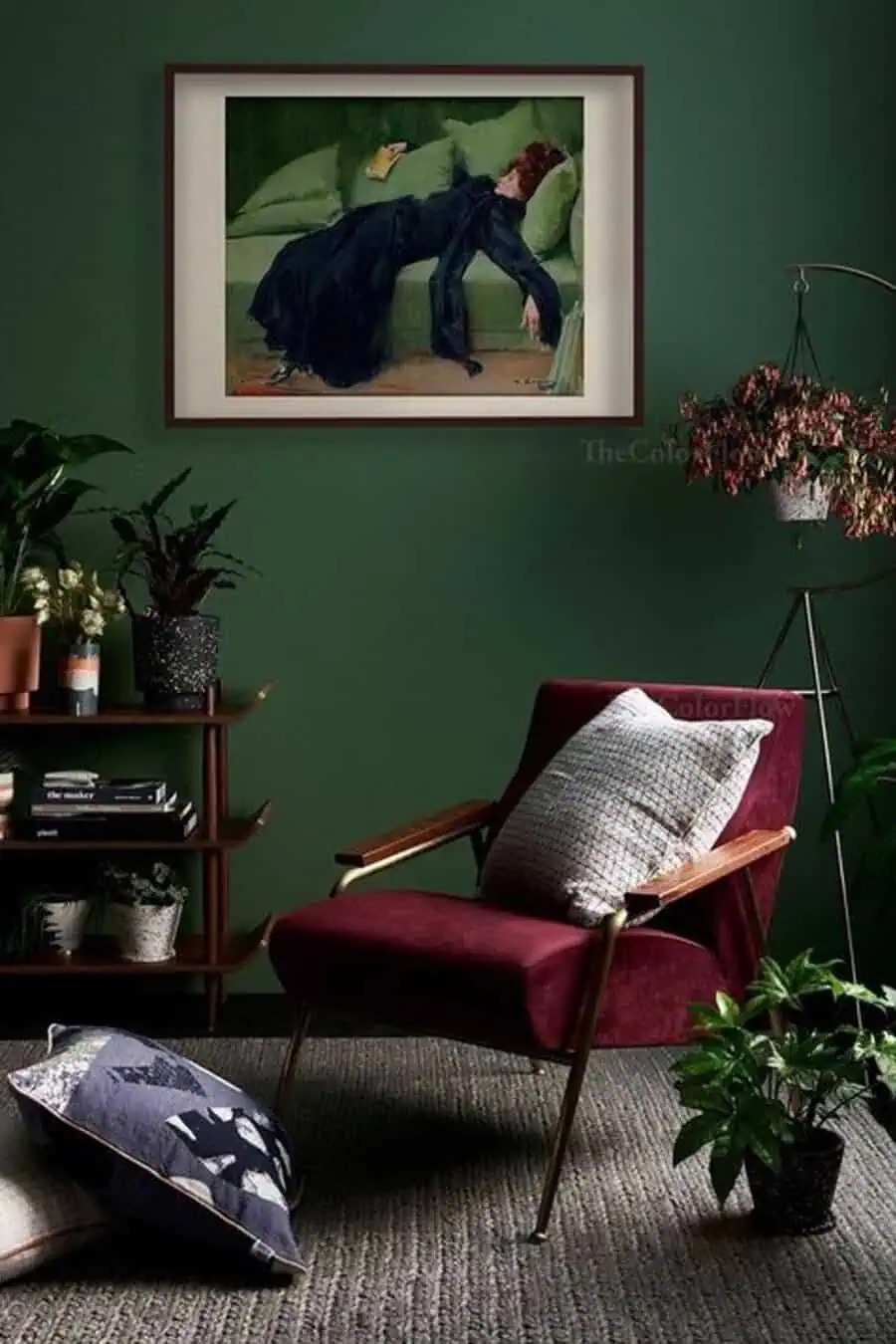 Stylish room with dark green walls, a burgundy chair, and framed artwork, accented by indoor plants.