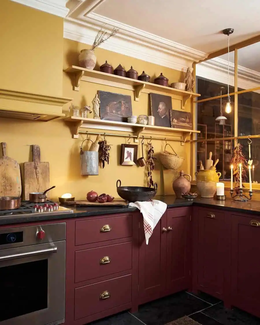 A cozy kitchen with warm yellow walls, red cabinets, open shelves with rustic decor, and a mix of ancient-inspired pottery.