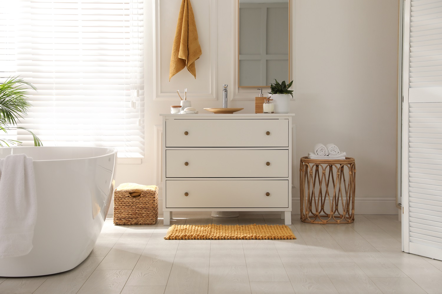 Modern bathroom featuring a white bathtub, wooden drawer, and a window with blinds