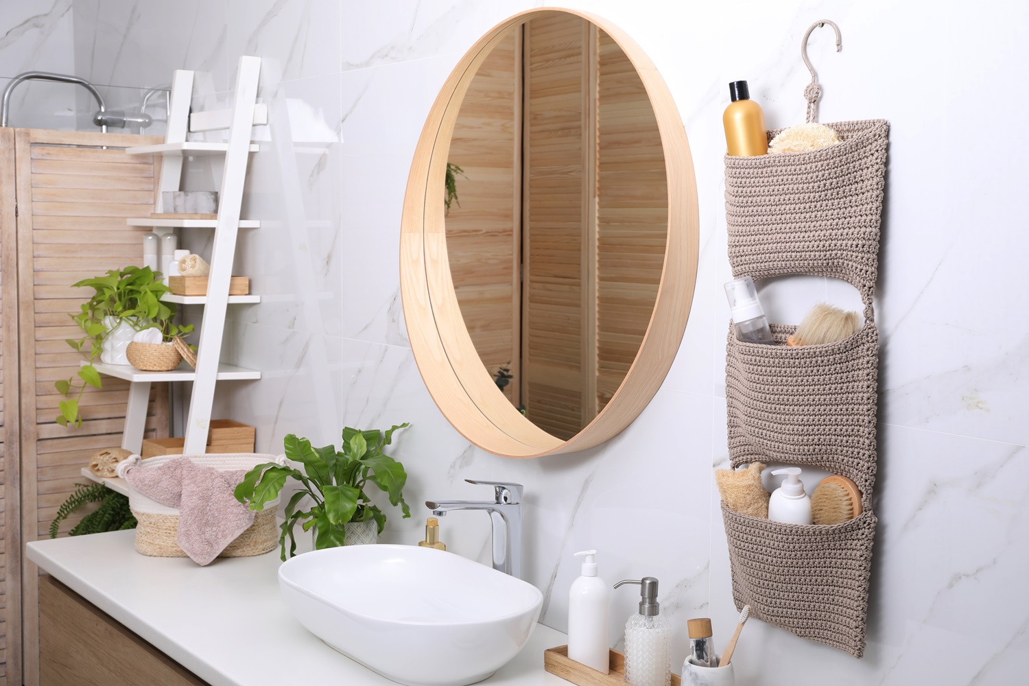 Modern bathroom featuring a round mirror, sink, hanging organizer, and potted plants