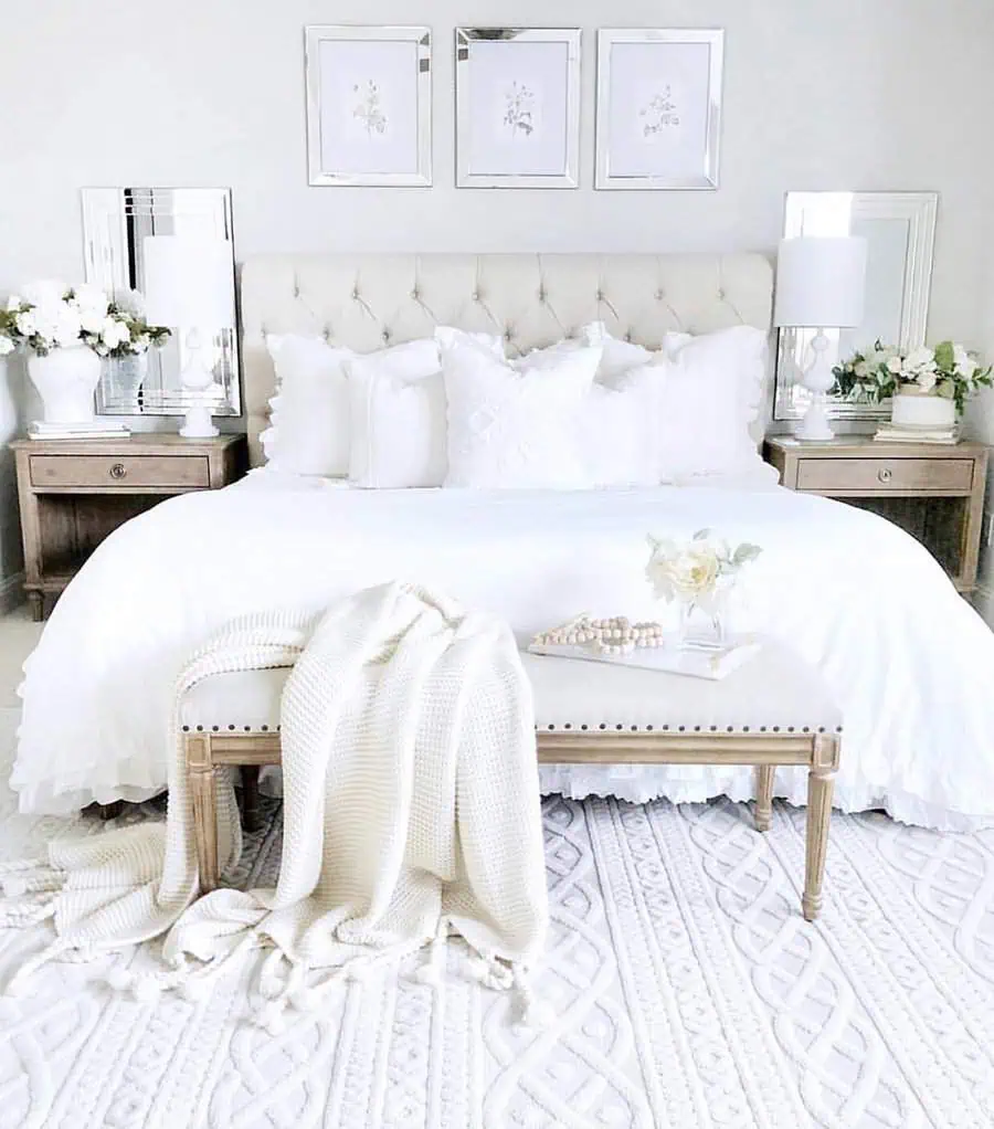 All-white bedroom with a tufted headboard, cozy layered bedding, and elegant decor accents.