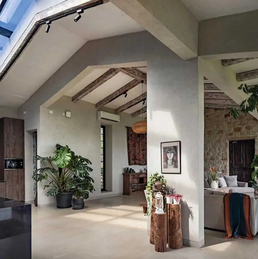 Modern living room with high ceilings, wooden beams, plants, and framed art on the wall