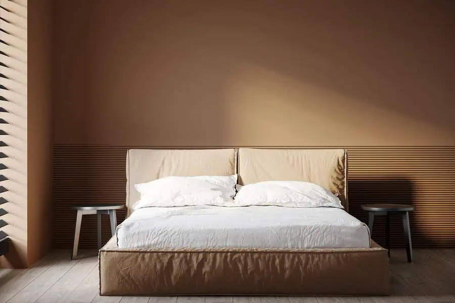 A minimalist bedroom with a double bed, white linens, and two small gray side tables.