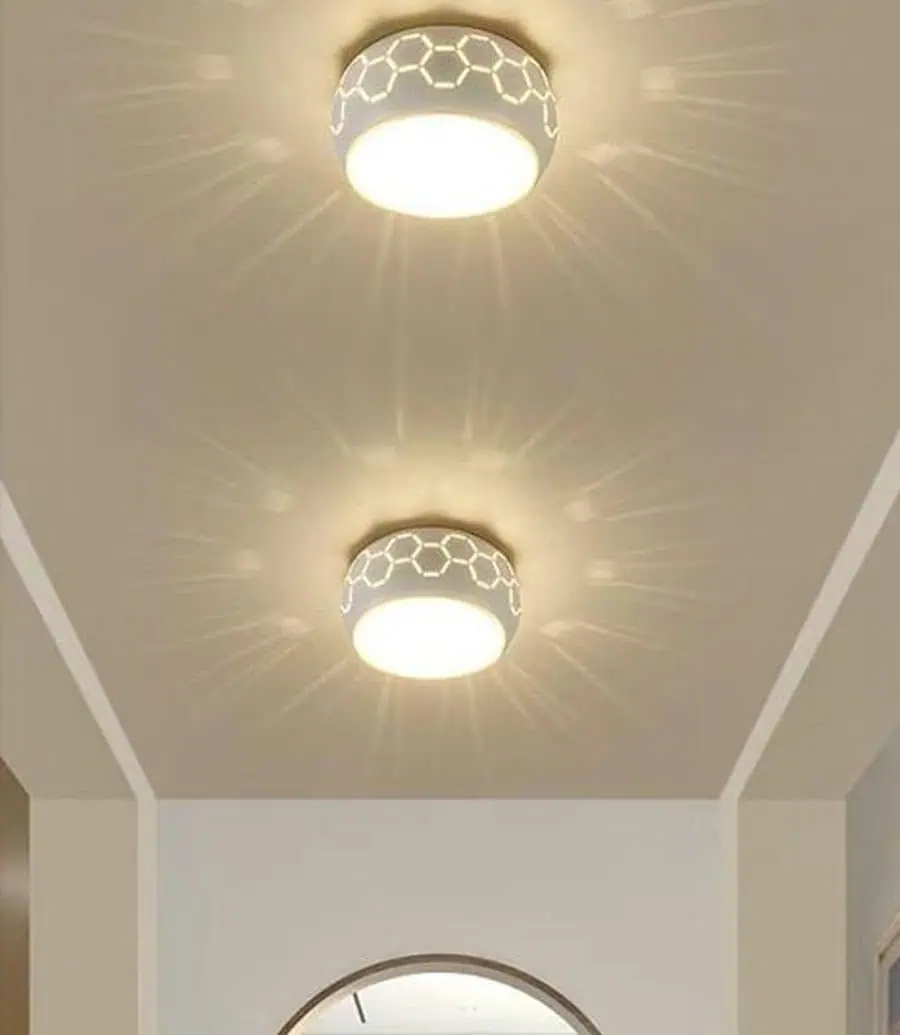 Two ceiling lights with hexagonal patterned fixtures casting a starburst light pattern on the ceiling