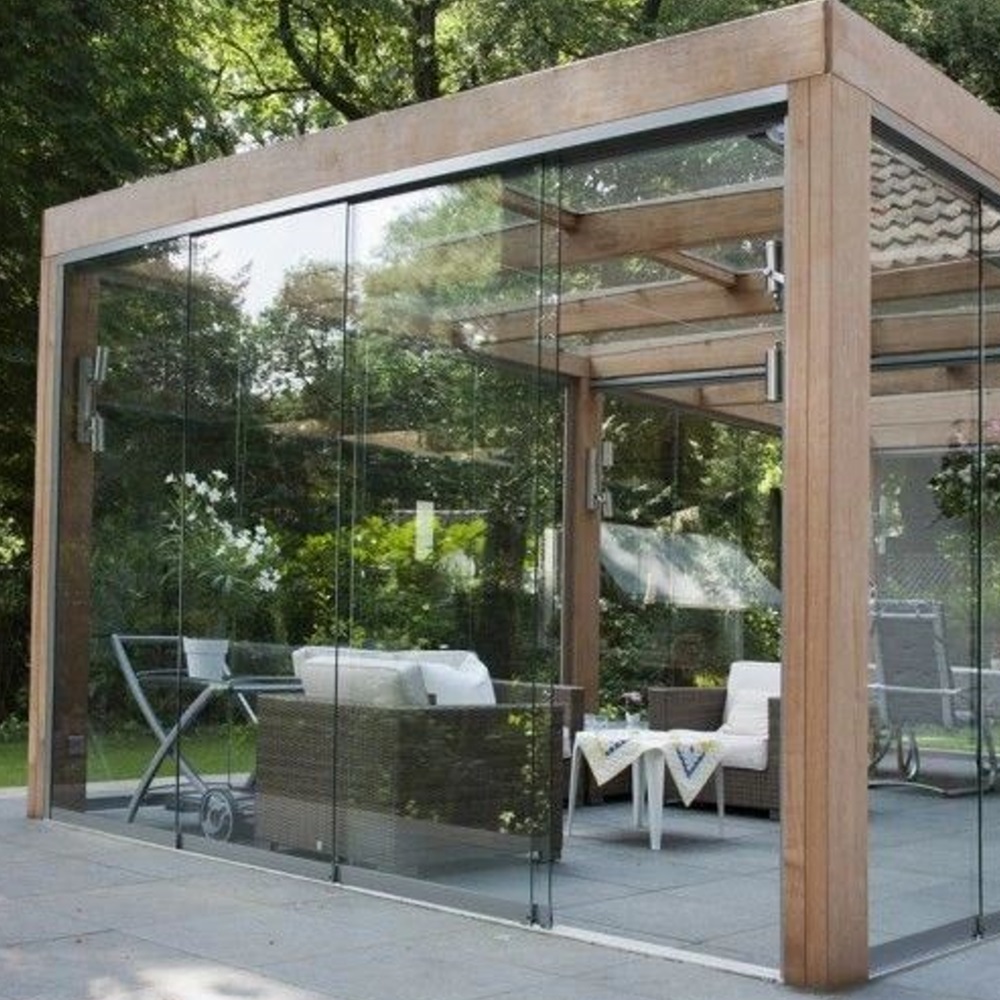 Glass-enclosed patio with wooden frame housing white furniture and garden decor