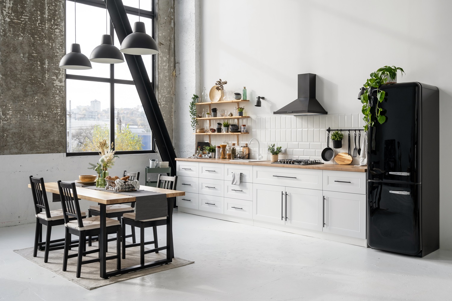 Modern kitchen featuring white cabinets, a black fridge, dining table, and large windows