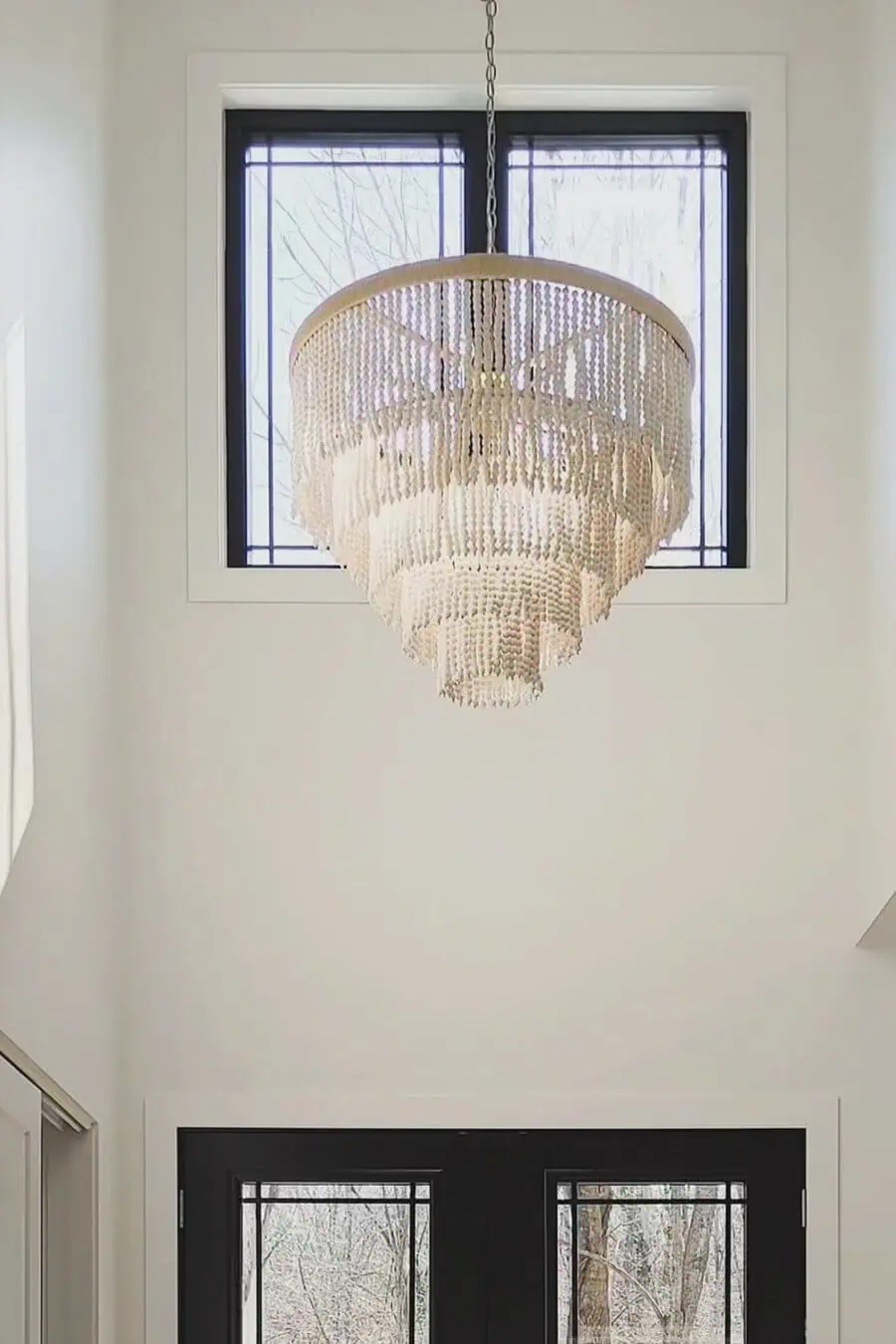 Elegant chandelier hanging in a modern entryway with large windows behind