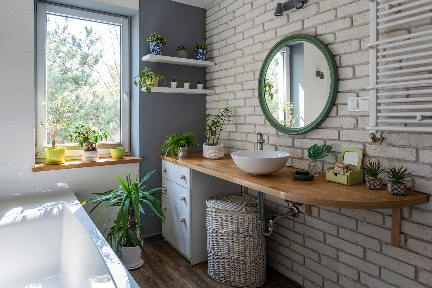 Modern bathroom with brick wall, round mirror, wooden counter, and various plants