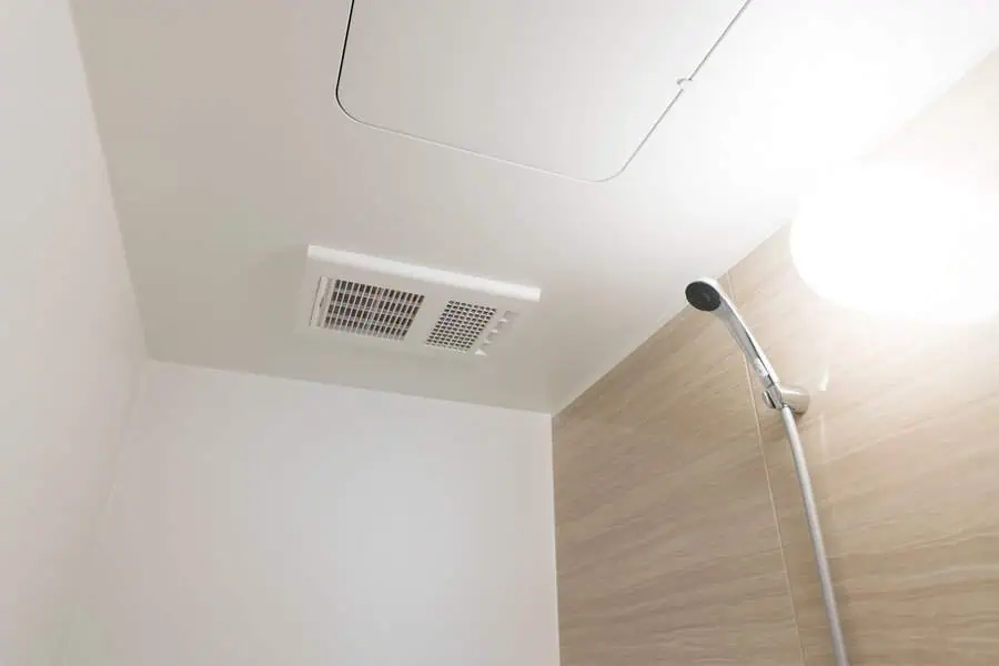 Shower area with a modern ceiling vent and a handheld showerhead mounted on a wall