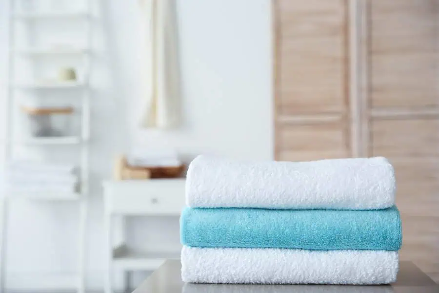 Stacked white and blue towels on a table in a clean, minimalist laundry room