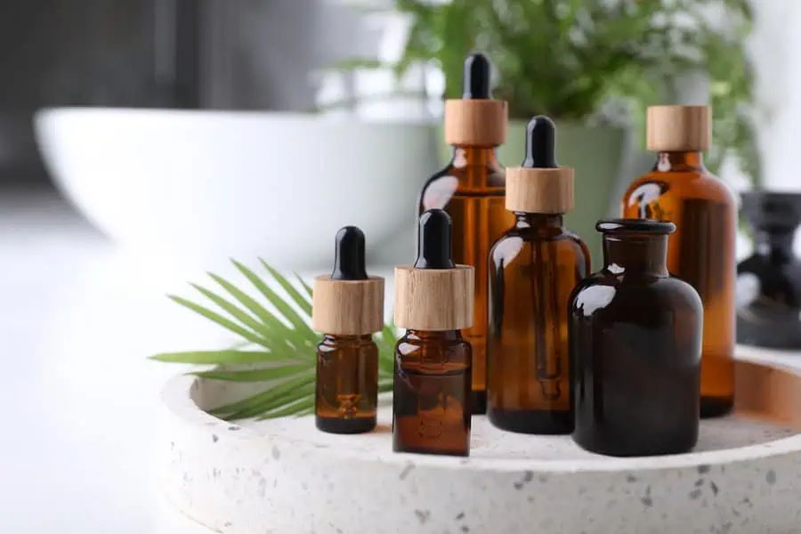 Brown glass dropper bottles on a tray with green foliage in the background