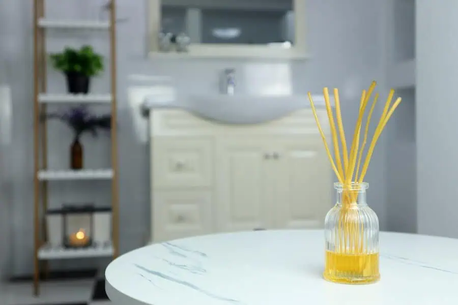 Reed diffuser on a white marble table in a modern, minimalist bathroom setting