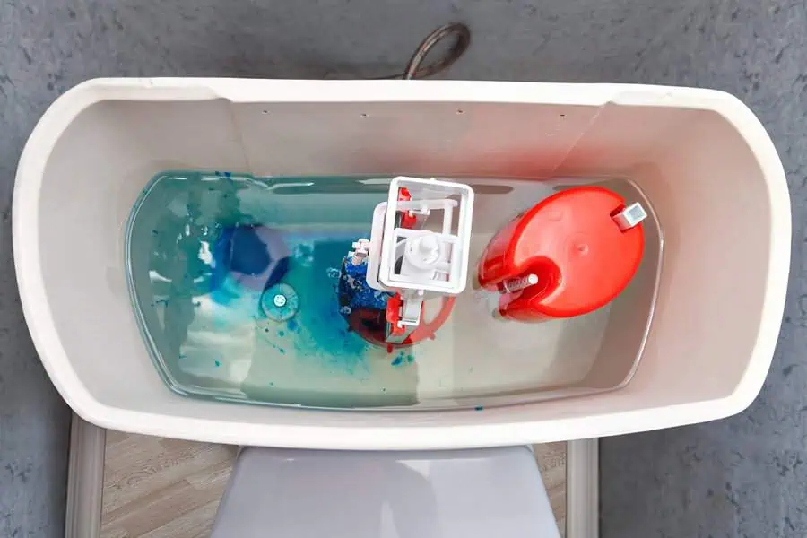 Inside view of a toilet cistern with water dyed blue and internal mechanisms visible