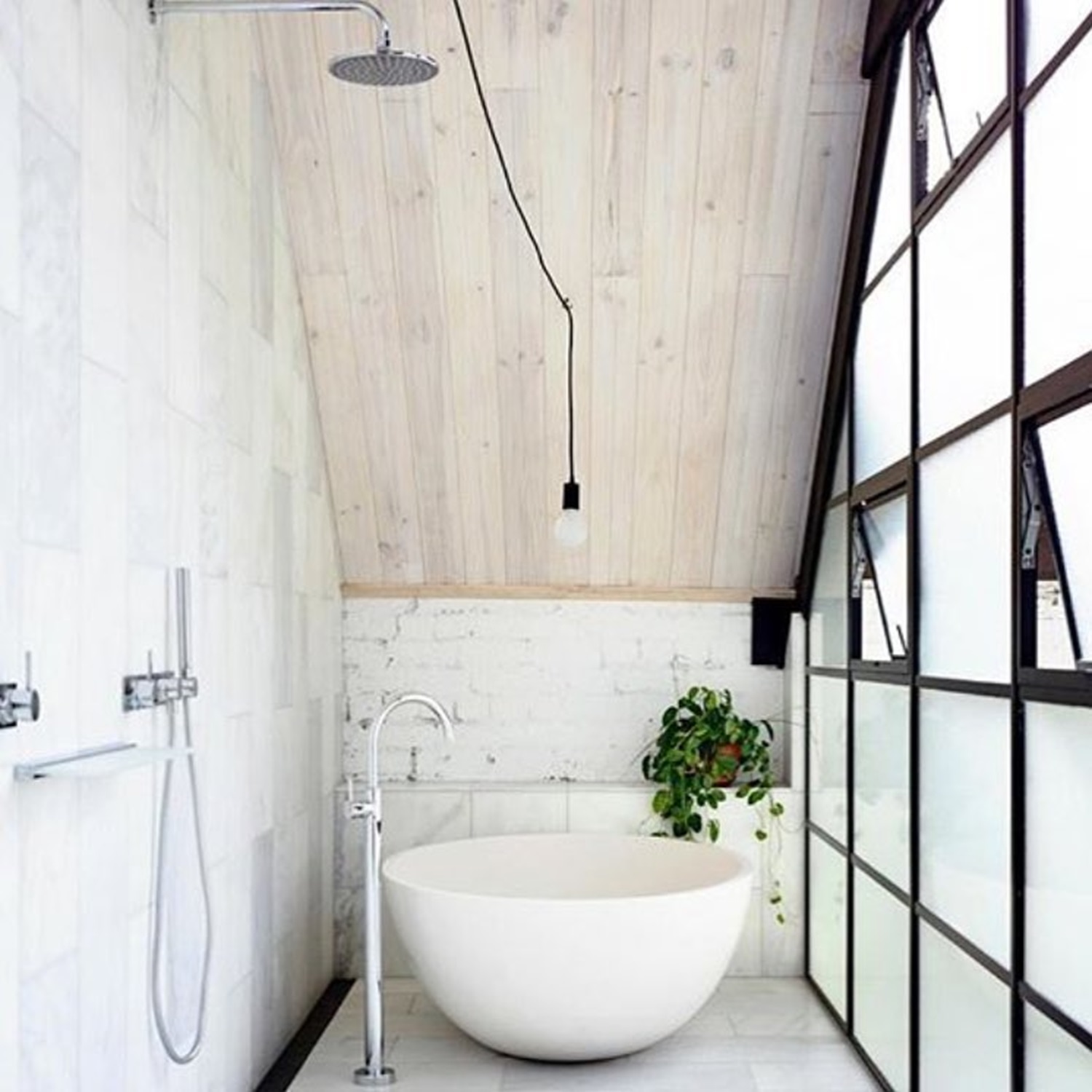 Minimalist bathroom featuring a freestanding tub, sloped ceiling, and hanging light bulb