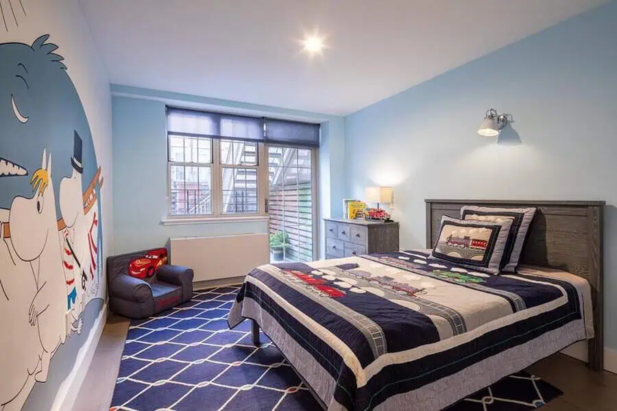 A child's bedroom featuring cartoon-themed decor, bed, dresser, and a small armchair by the window