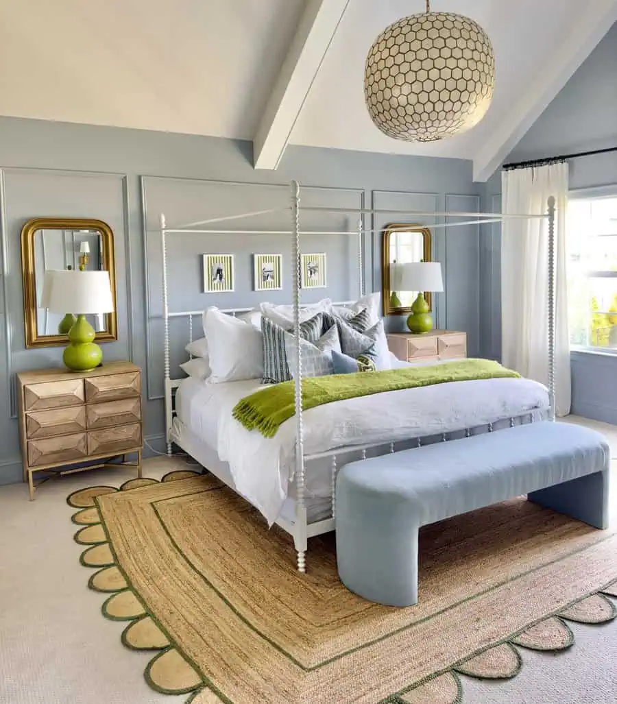 Elegant bedroom with a four-poster bed, green accents, and light blue walls and bench