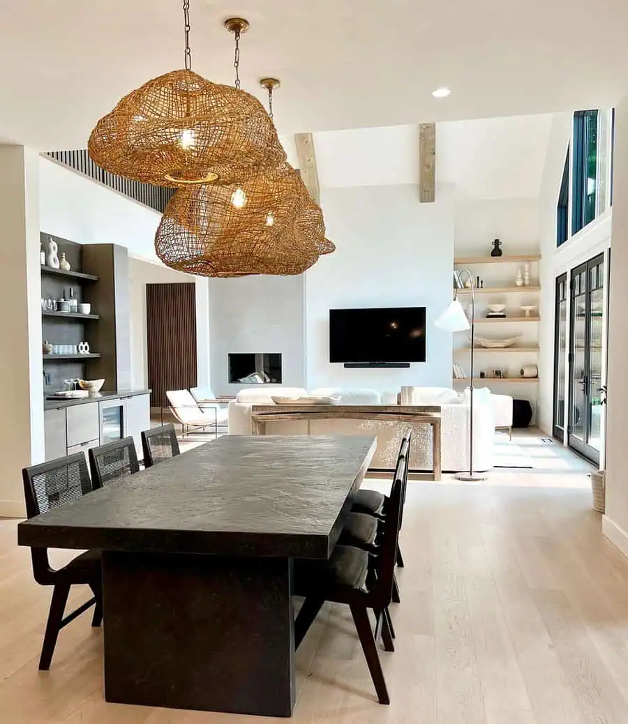 Modern open-concept living and dining area with natural light, wicker pendant lights, and dark dining table with black chairs