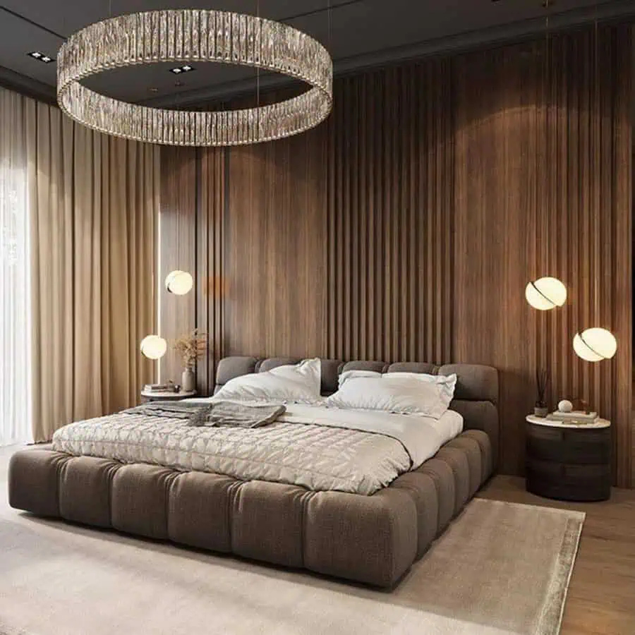 Modern bedroom with a plush bed, wooden accent wall, circular chandelier, and globe lights.