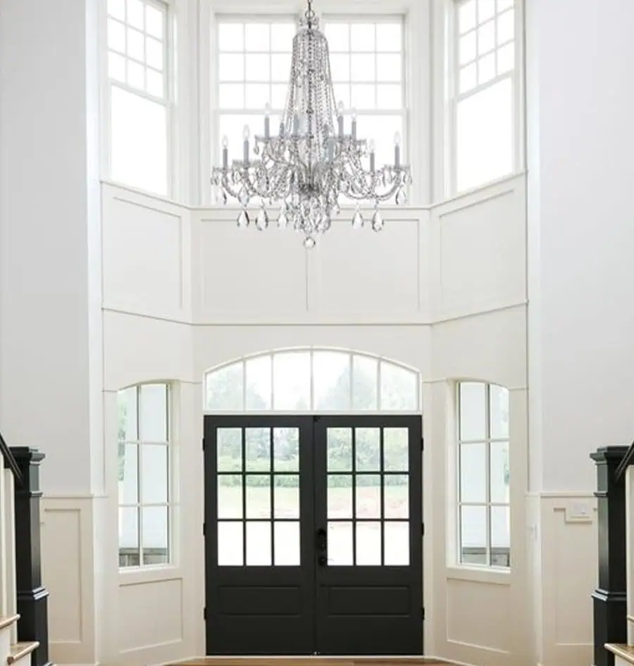 A grand entryway with large windows, featuring a stunning crystal chandelier that adds elegance and sparkle.