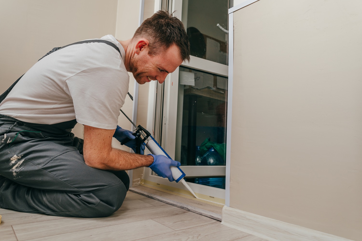 Applying caulking to the base of a doorframe