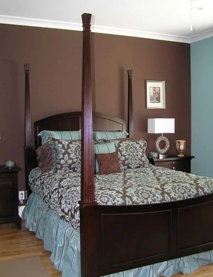 Bedroom with a dark wood four-poster bed, teal and brown bedding, and a nightstand with a lamp.