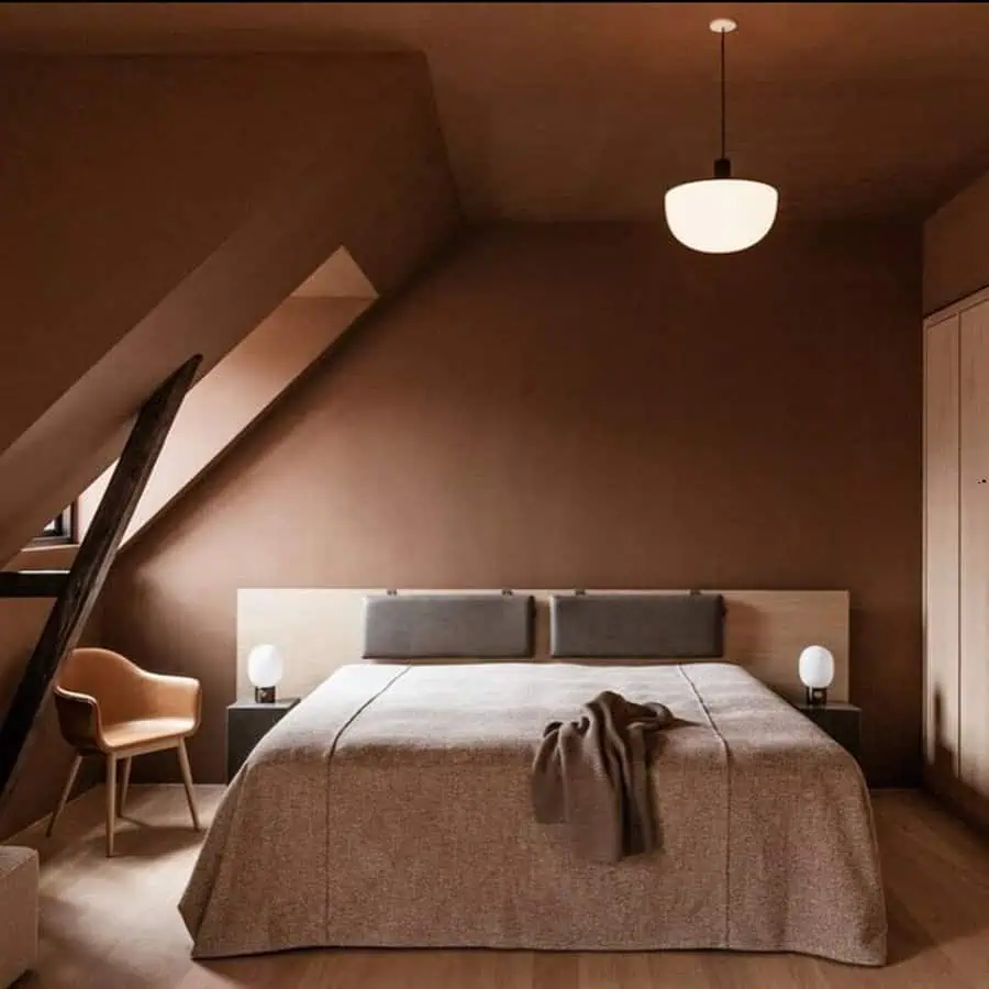 A modern bedroom with a double bed, hanging light, chair, and two nightstands with lamps.