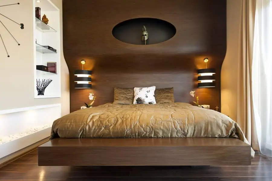 Modern bedroom with a floating wooden bed, built-in shelves in the wall, and ambient lighting.