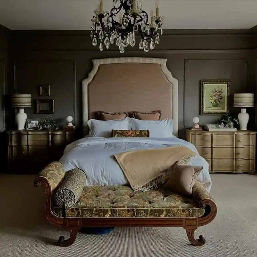 Luxurious bedroom with a large upholstered bed, wooden furniture, a chandelier, and a floral-patterned bench at the foot