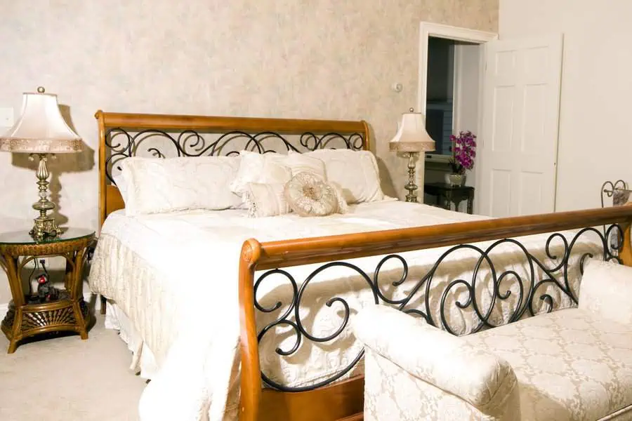 Elegant bedroom with a wooden bed featuring ornate metal headboard and footboard, and two bedside tables