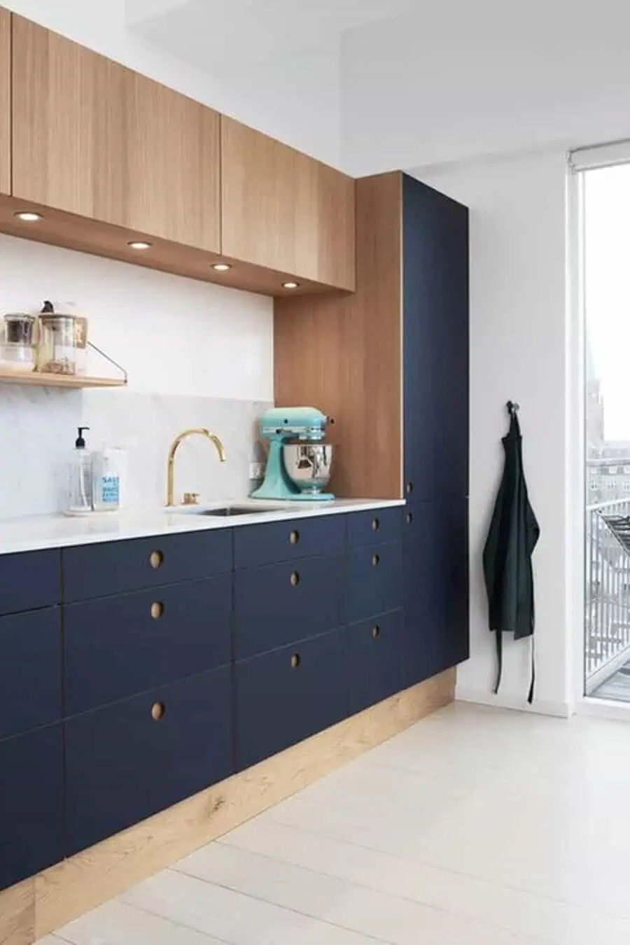 Modern kitchen with blue cabinets, wooden accents, and a light blue mixer on the countertop