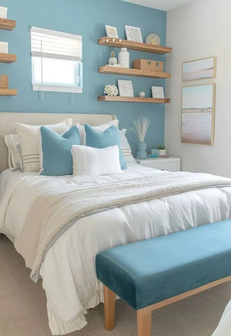 A cozy bedroom with blue accents, floating shelves, and a teal bench at the foot of the bed