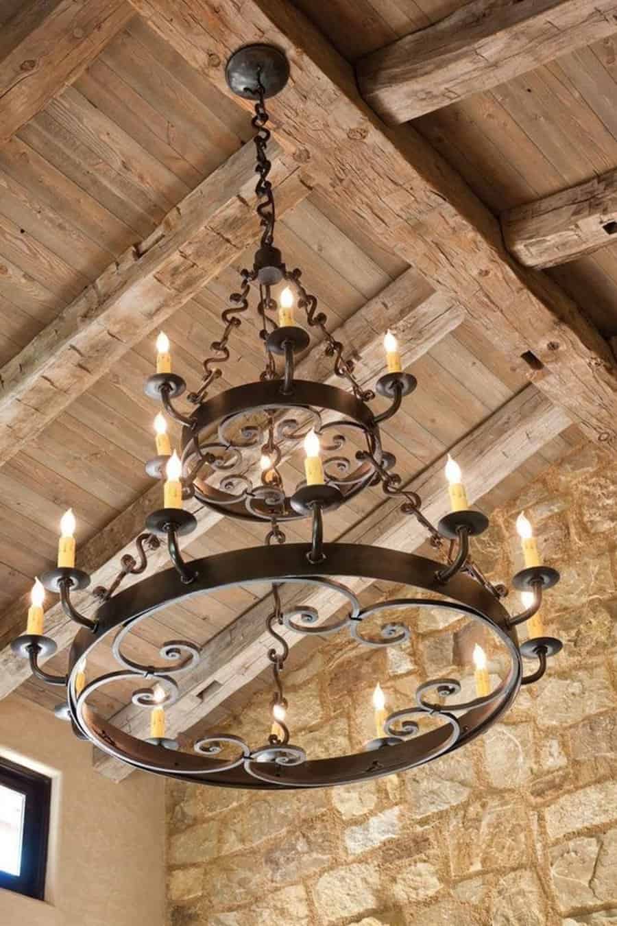 Rustic iron chandelier with multiple candle-shaped lights hanging from a wooden-beamed ceiling