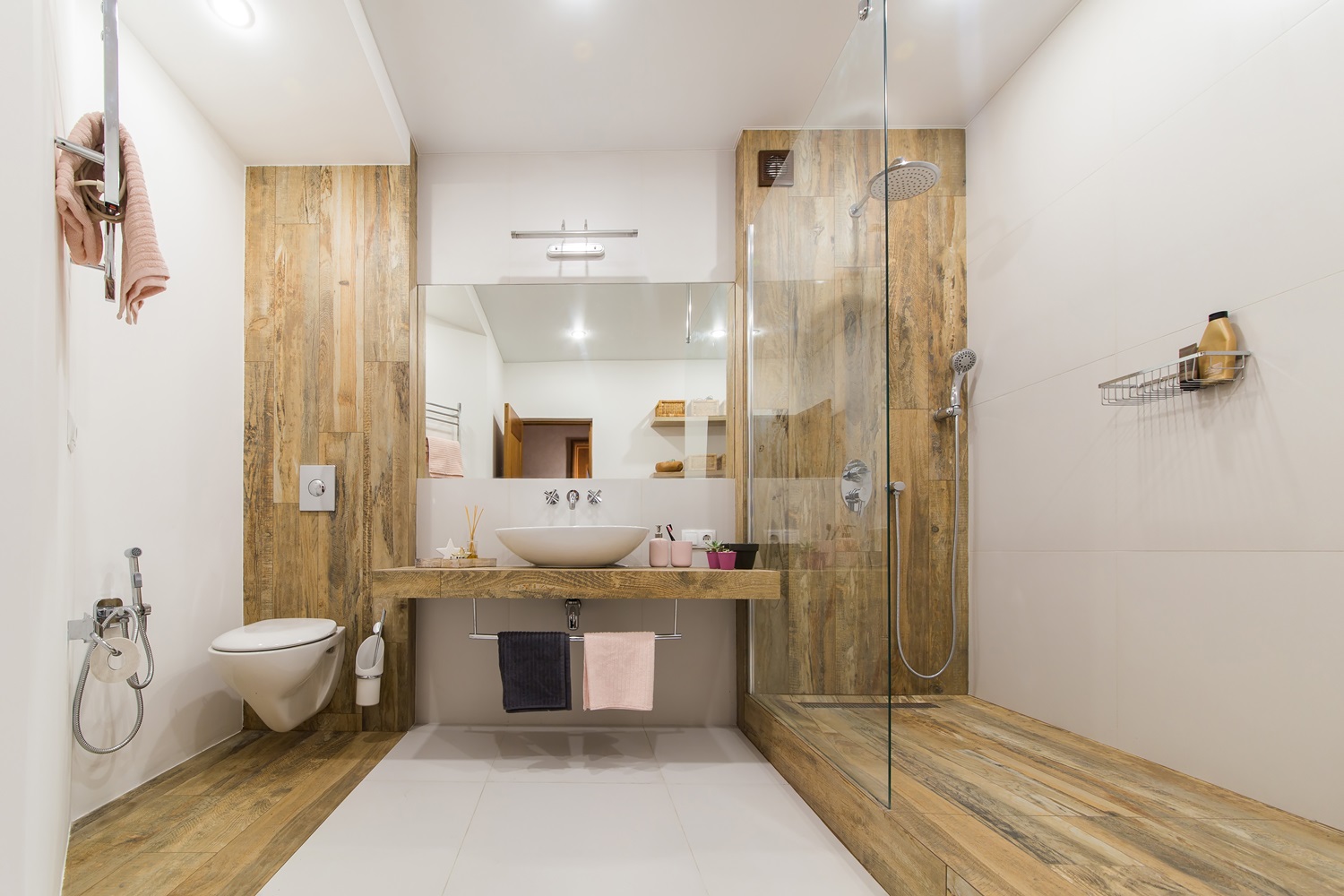 Modern bathroom featuring wooden accents, shower, toilet, and sink with a large mirror