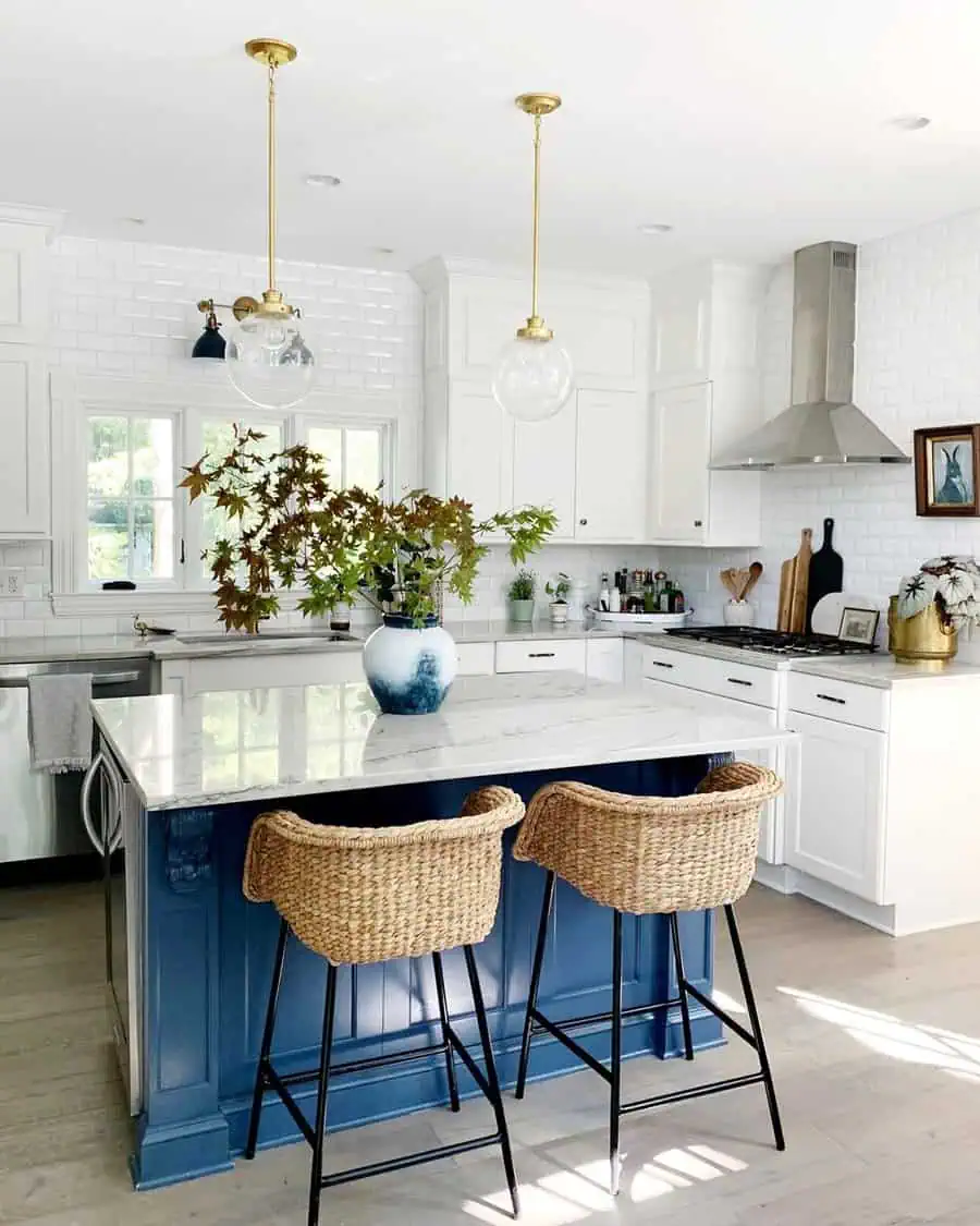 Modern kitchen with white cabinets, blue island, wicker stools, and hanging pendant lights