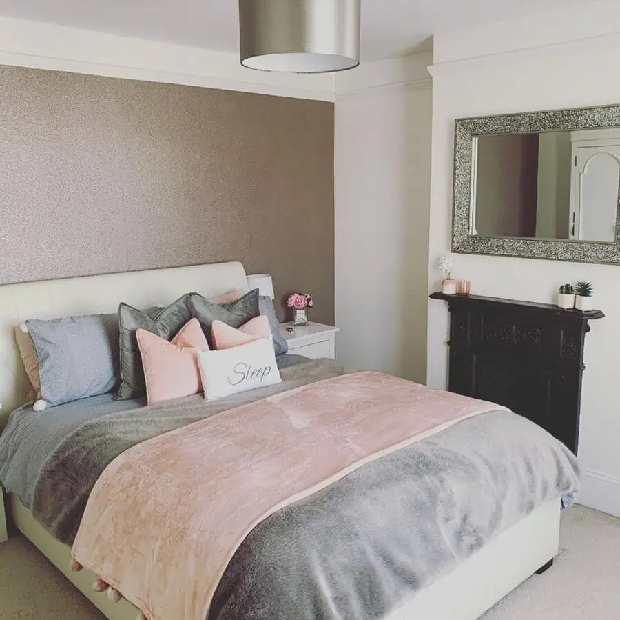 Cozy bedroom with a neutral color palette, featuring a plush bed, mirror, and decorative fireplace