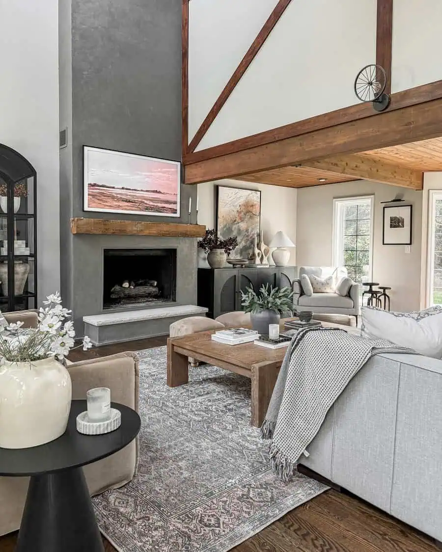 Modern living room with vaulted ceiling, cozy seating, large rug, fireplace, and rustic wooden accents