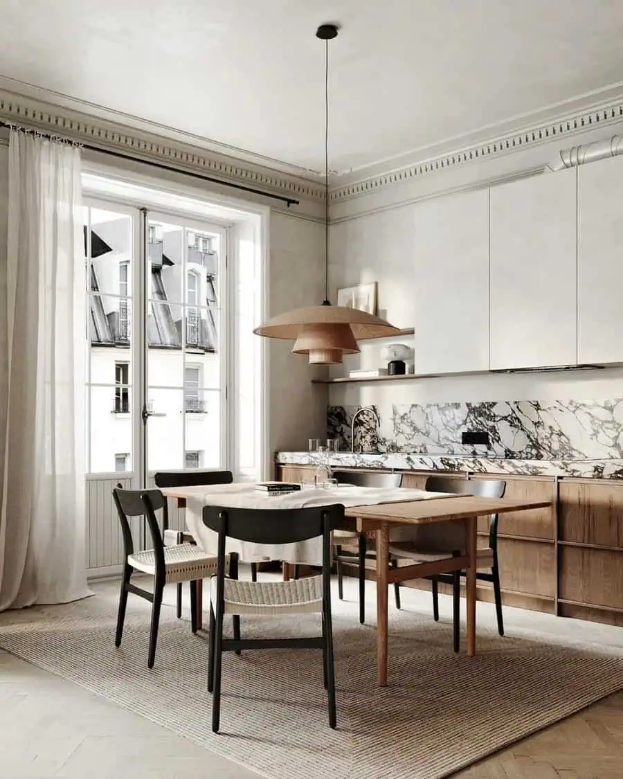 Modern kitchen featuring wooden cabinets, a marble backsplash, a round dining table, and chairs beneath a large pendant light