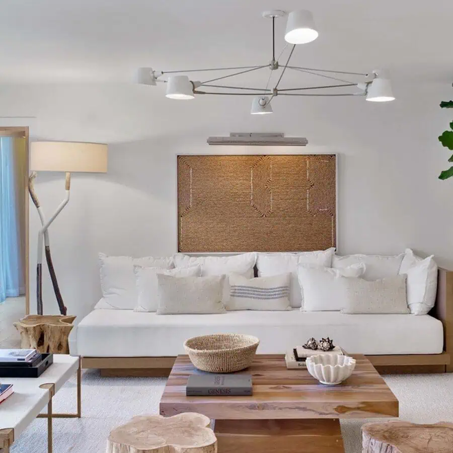 A modern living room featuring a white sofa, wooden coffee table, light fixtures, and minimalist decor