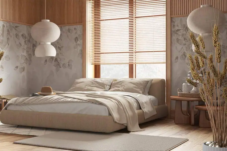 A cozy bedroom with a large bed, wooden accents, bedside tables, wall lamps, and natural light streaming through the blinds