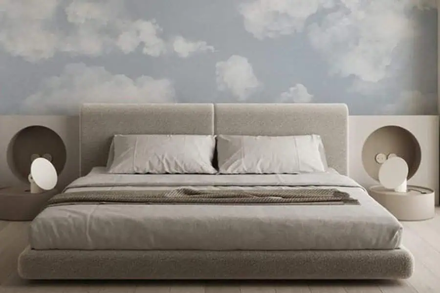 Modern bedroom featuring a beige bed, gray bedding, and a cloud mural on the wall behind the bed