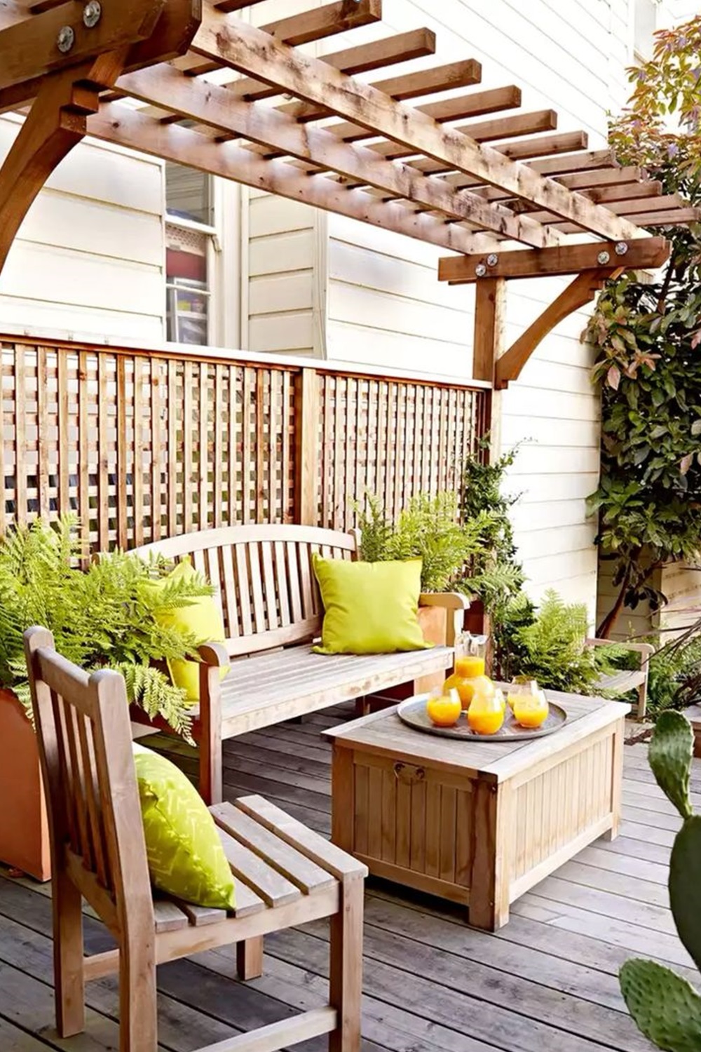 Cozy wooden patio with pergola, seating, potted plants, and citrus drinks on a table