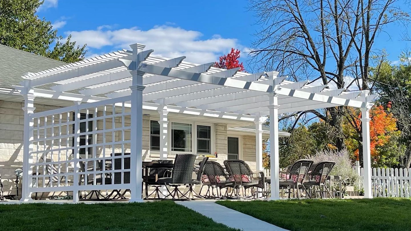 White pergola with outdoor dining set on a patio in a sunny backyard