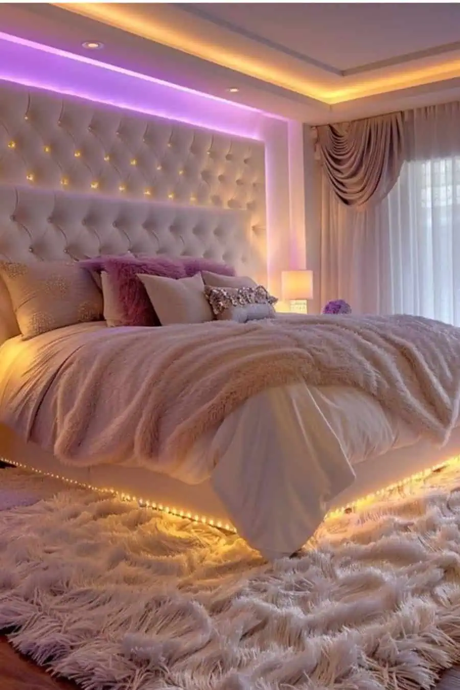 Luxurious white bedroom with ambient lighting, tufted headboard, fluffy bedding, and soft rug.