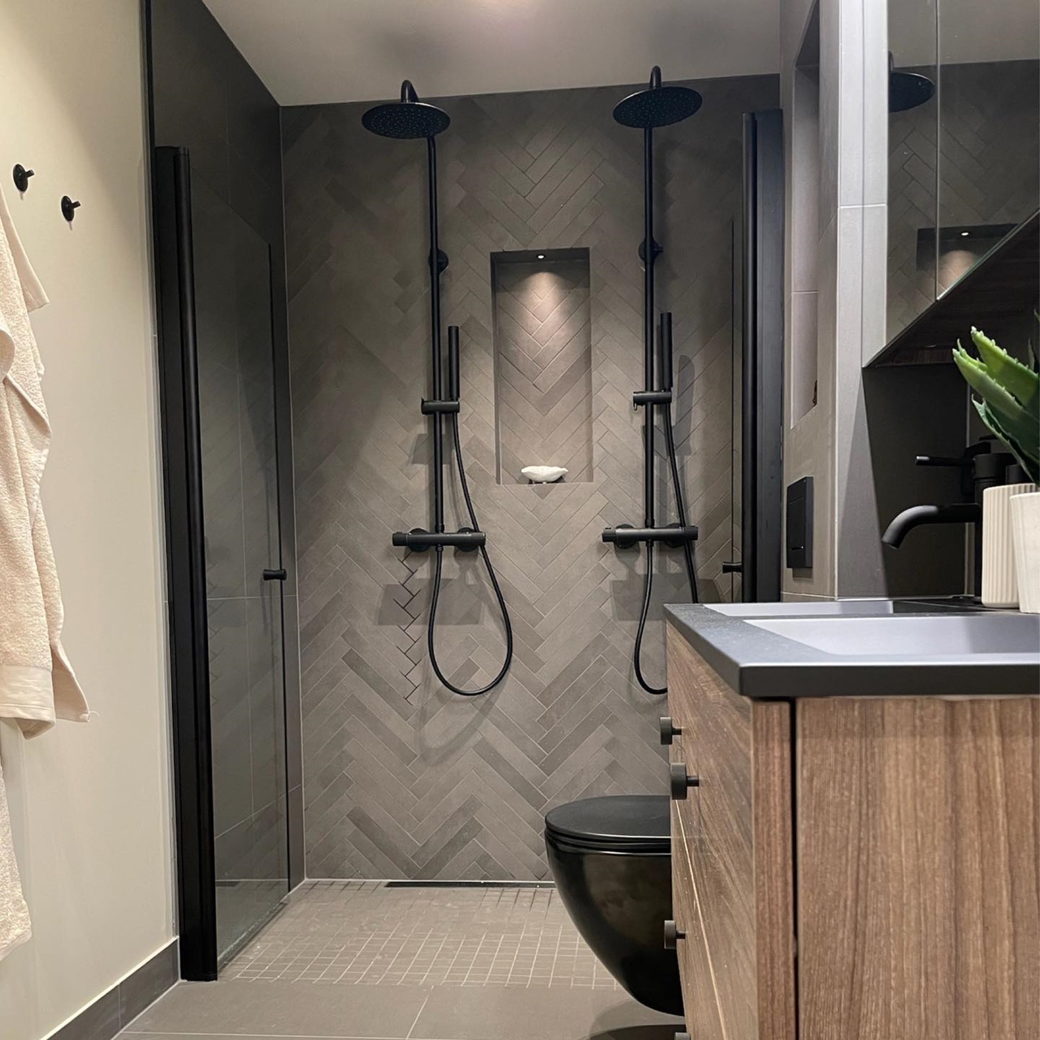 Modern bathroom featuring dual showerheads, wooden vanity, and black fixtures