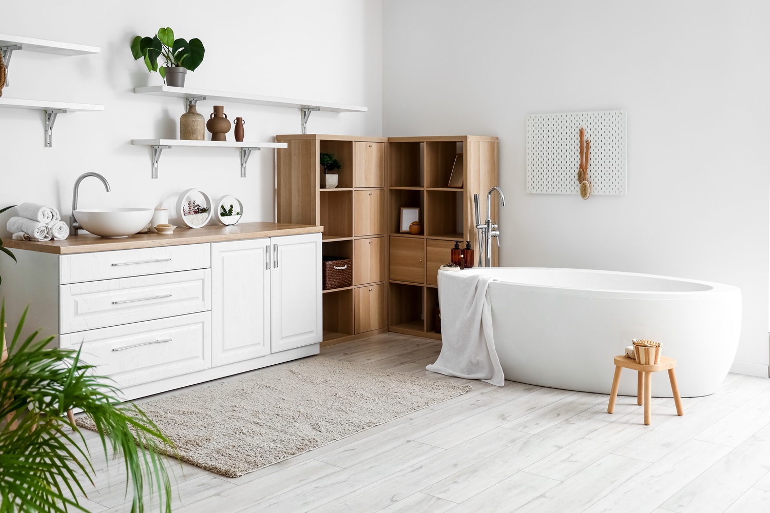 Modern bathroom featuring a freestanding tub, wooden shelves, and white cabinets